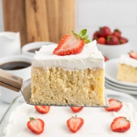 a slice of Tres Leches Cakes topped with a slice of strawberry on a spatula