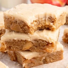 Apple brownies stacked on parchment paper with bite taken out of the top piece