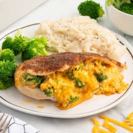 A dinner plate with Broccoli and Cheese Stuffed Chicken Breast, potatoes, and broccoli.