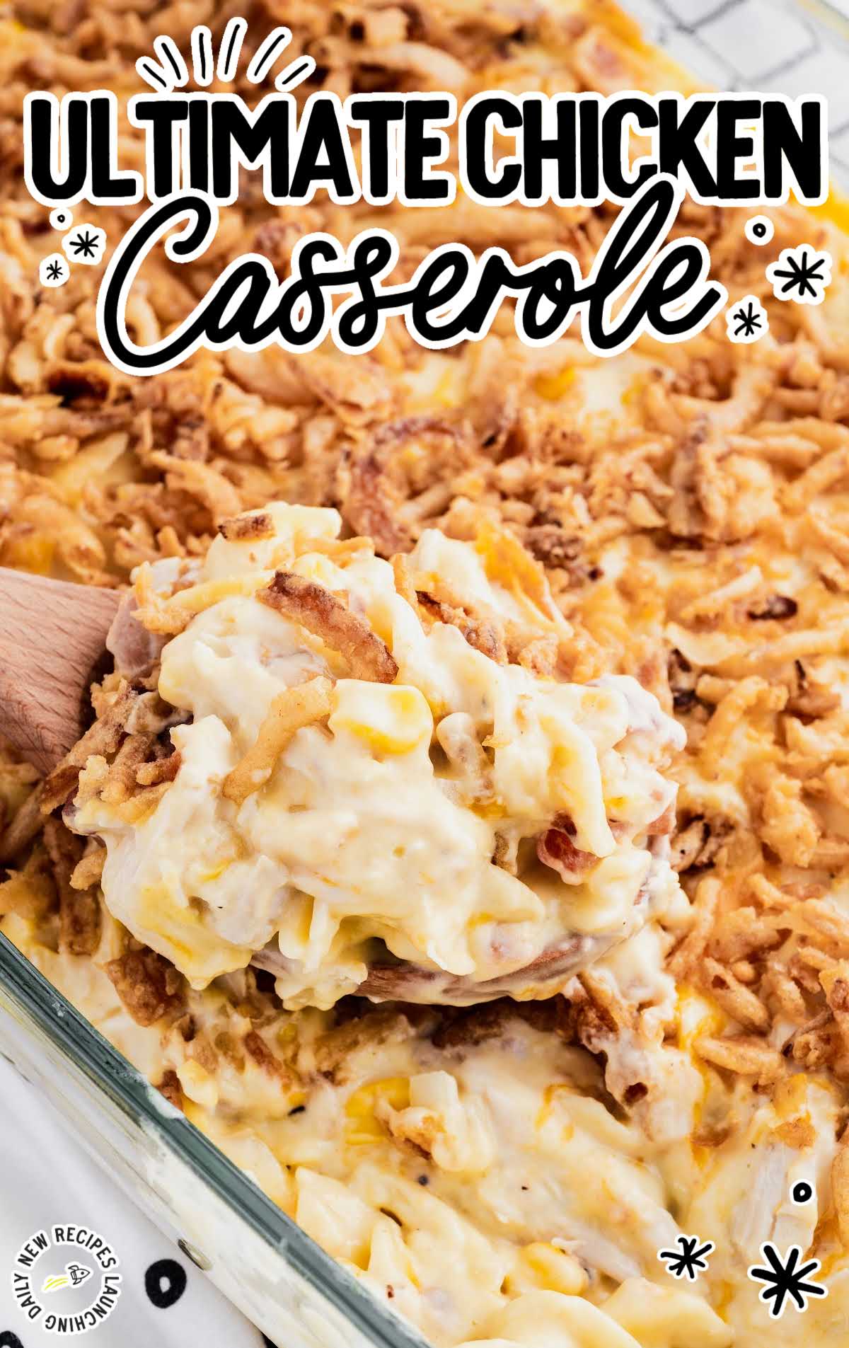 Spoonful of creamy chicken casserole being scooped from a baking dish topped with crispy fried onions.
