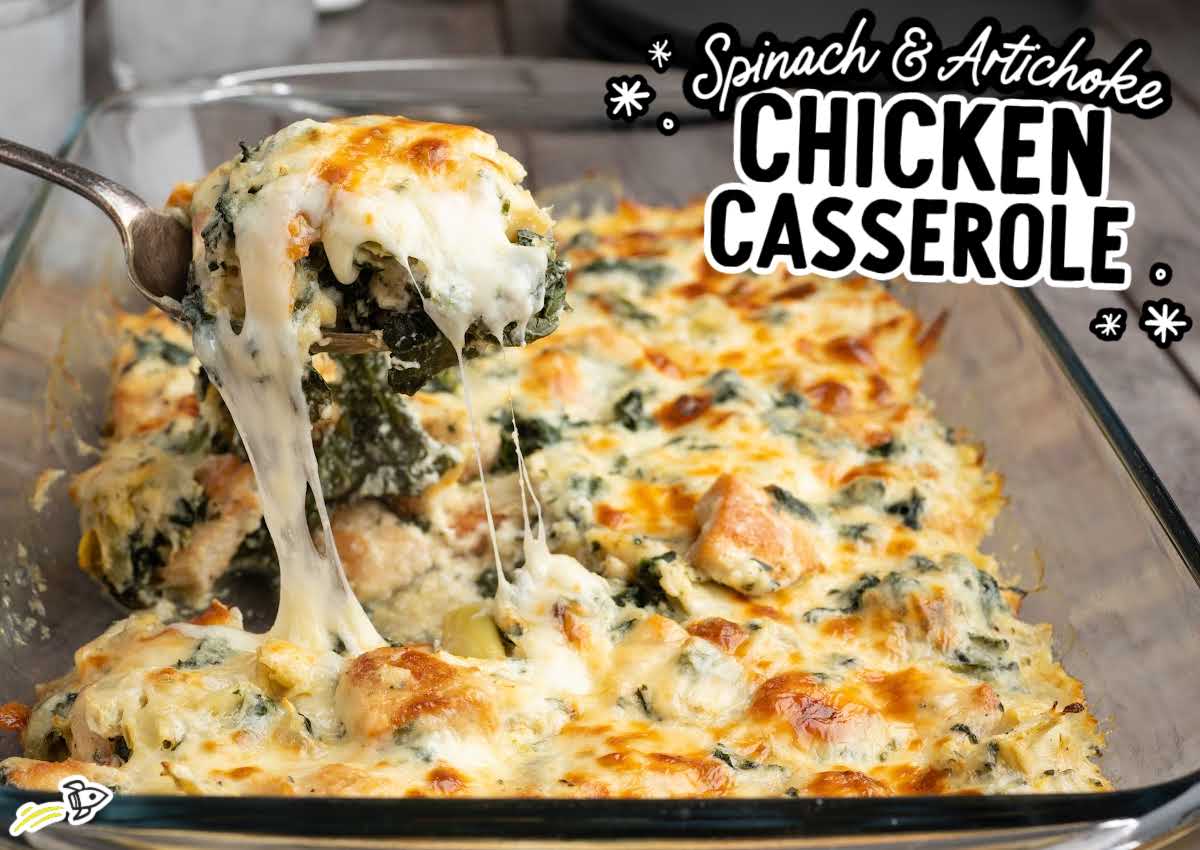 Overhead view of spinach and artichoke chicken casserole in a glass baking dish with a cheesy serving lifted on a spoon.
