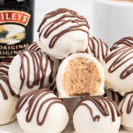 bailey's cheesecake balls on a white plate. one has a bite out of it.