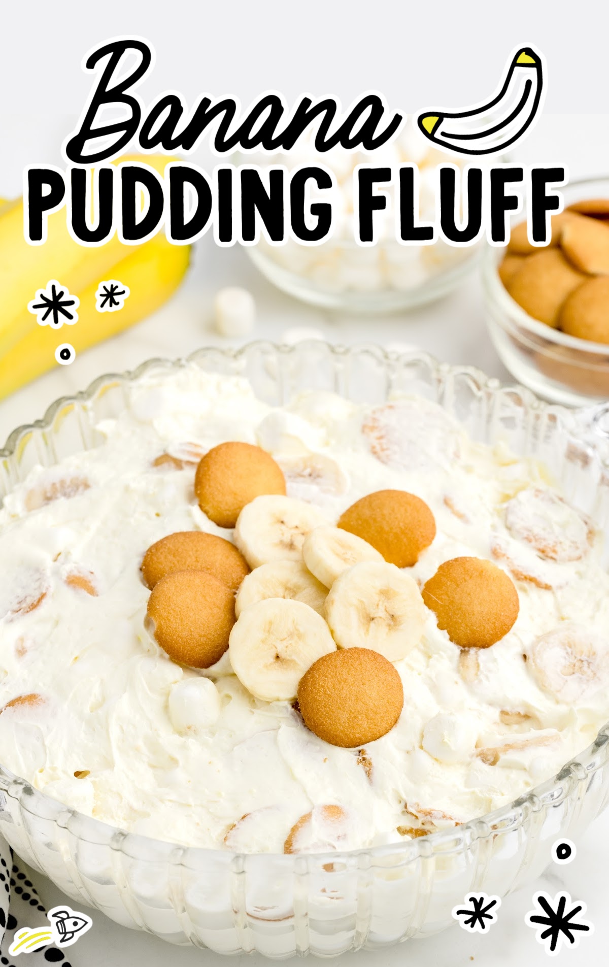 A bowl of banana pudding fluff with banana slices and nilla wafers on top. 