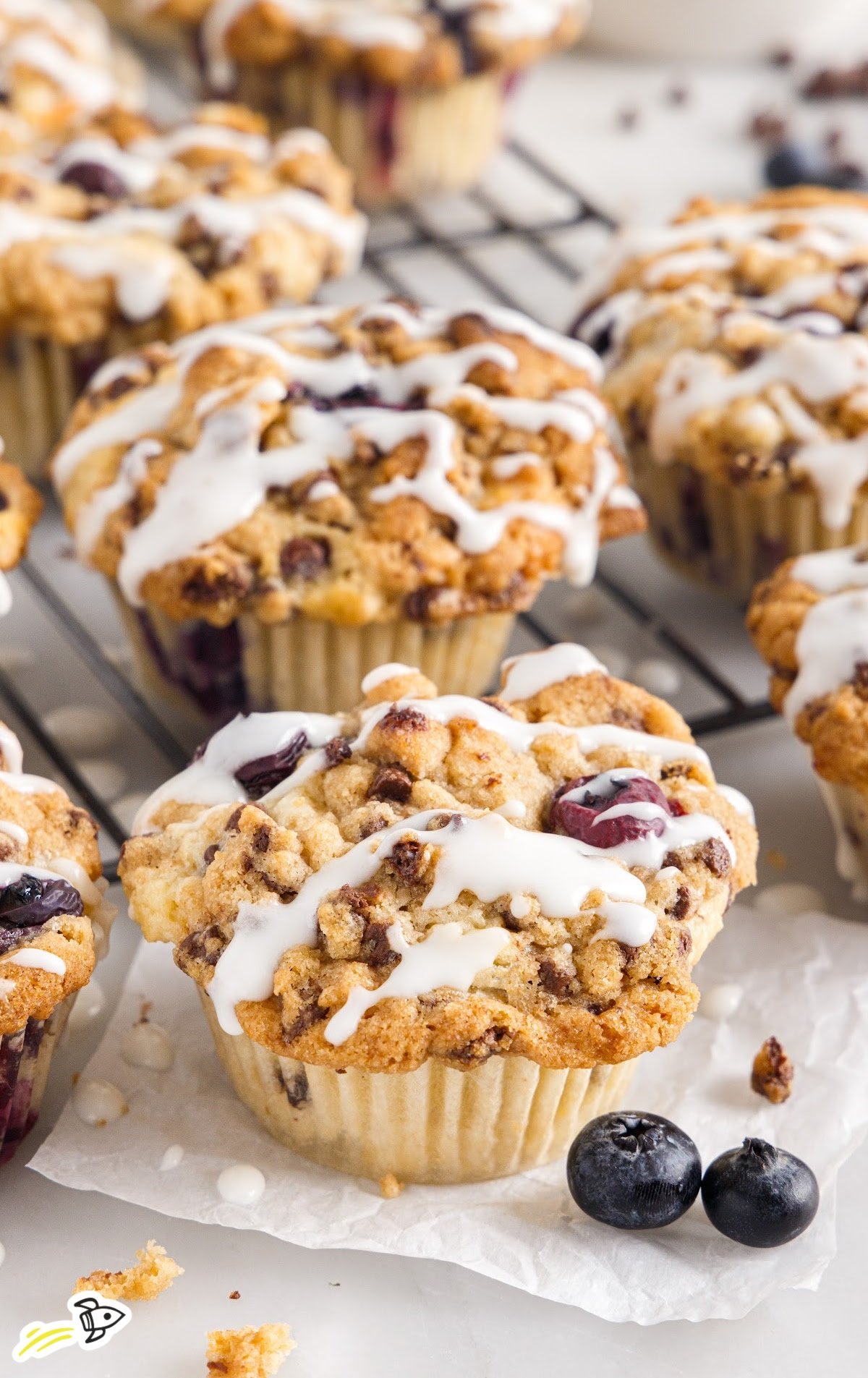 Blueberry Chocolate Chip Muffins covered in drizzle on a serving plate. 