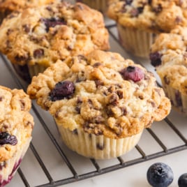 A cooling rack is covered in Blueberry Chocolate Chip Muffins.