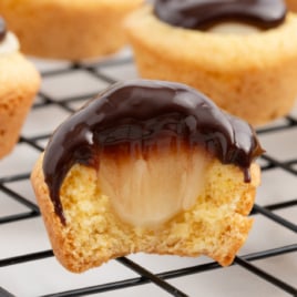 A black wire cooling rack covered in cookie cups, one with a bite out of it