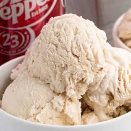 Dr Pepper ice cream in a bowl with multiple scoops beside Dr Pepper soda cans