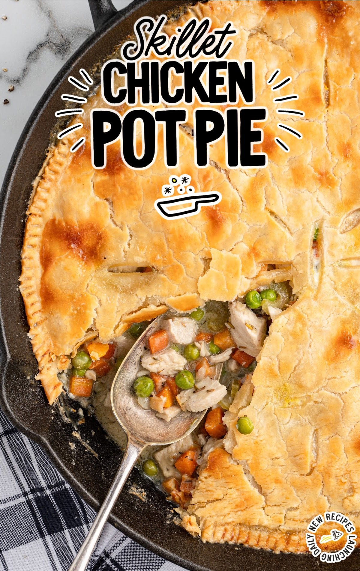 A skillet chicken pot pie is baked, with a serving spoon scooping out vegetables and crust.