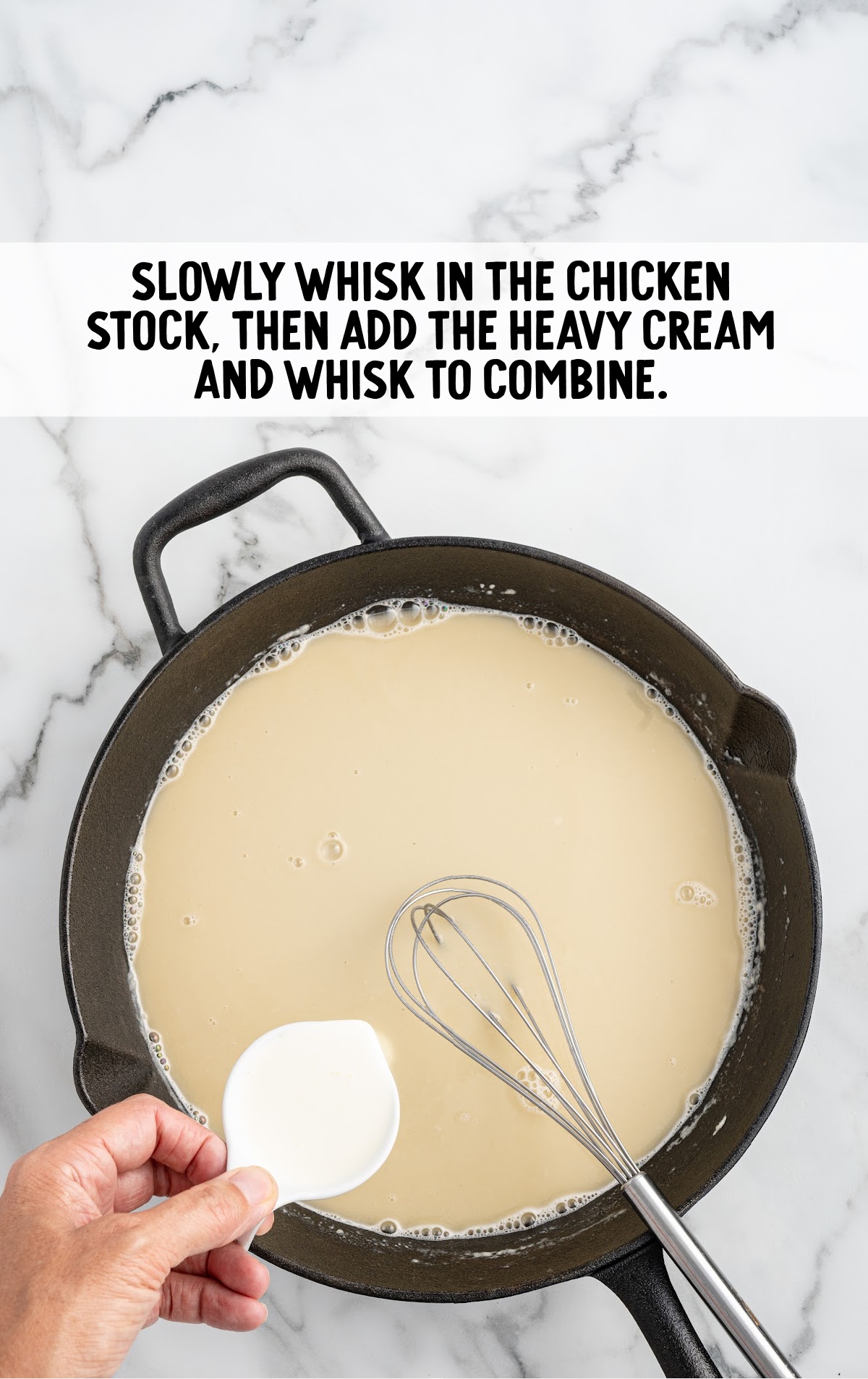 A skillet full of broth and heavy cream is being poured into it.