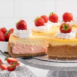 Strawberries and Cream Cheesecake topped with whipped topping and a strawberry on a plate