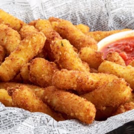 A bowl of fried stuffed ziti fritta and a smaller bowl of tomato sauce.