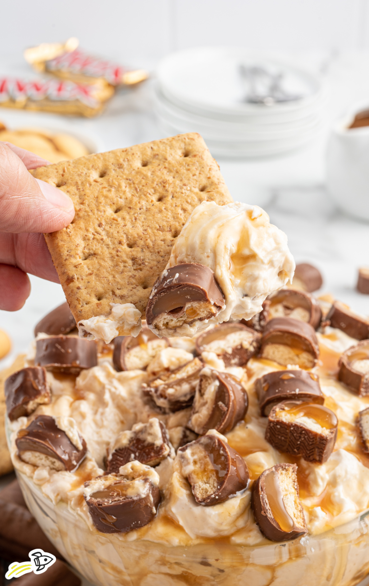 A closeup shot of a scoop of twix dip on a graham cracker