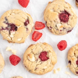 White chocolate and raspberry cookies on a piece of white parchment.