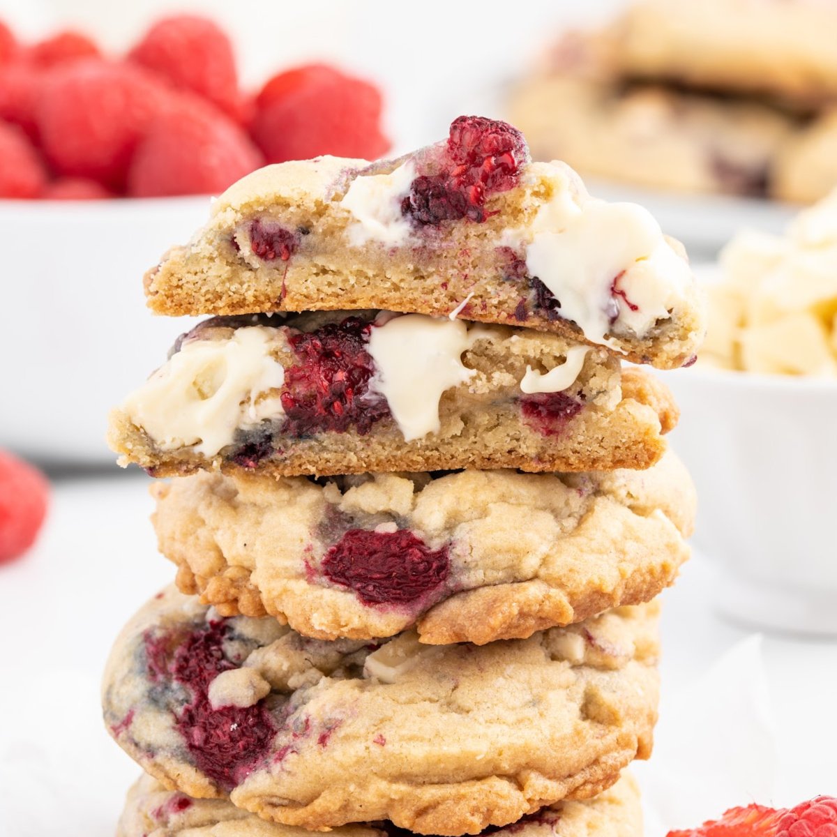 A stack of White Chocolate and Raspberry Cookies with the ones on top split open to show the inside.