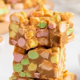 Close-up of peanut butter marshmallow squares with bright pastel marshmallows surrounded by smooth, chewy peanut butter coating.