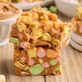 Stack of colorful peanut butter marshmallow squares on a wooden surface showing soft, chewy texture and pastel mini marshmallows.
