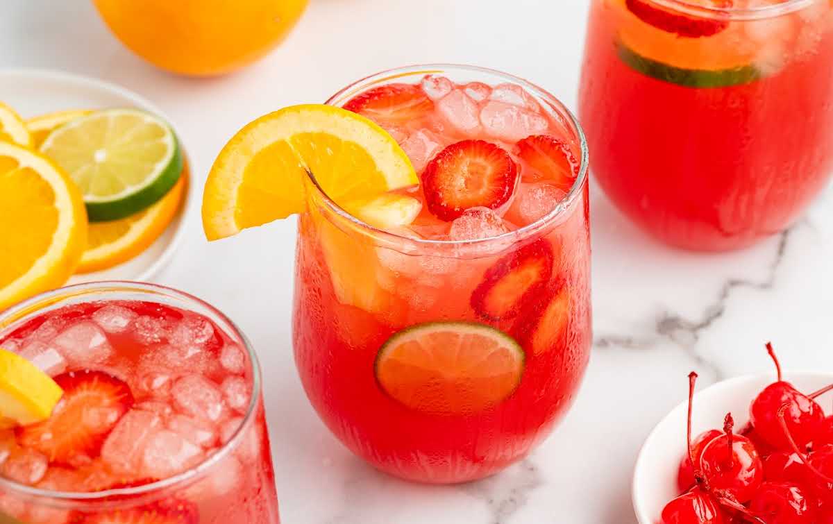 Close-up top view of vibrant red party punch garnished with orange and lime slices, perfect for parties and summer gatherings.