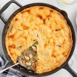 A whole pan of Skillet Chicken Pot Pie with a piece taken out of it.