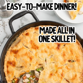 A whole skillet of chicken pot pie with a serving spoon scooping out vegetables.