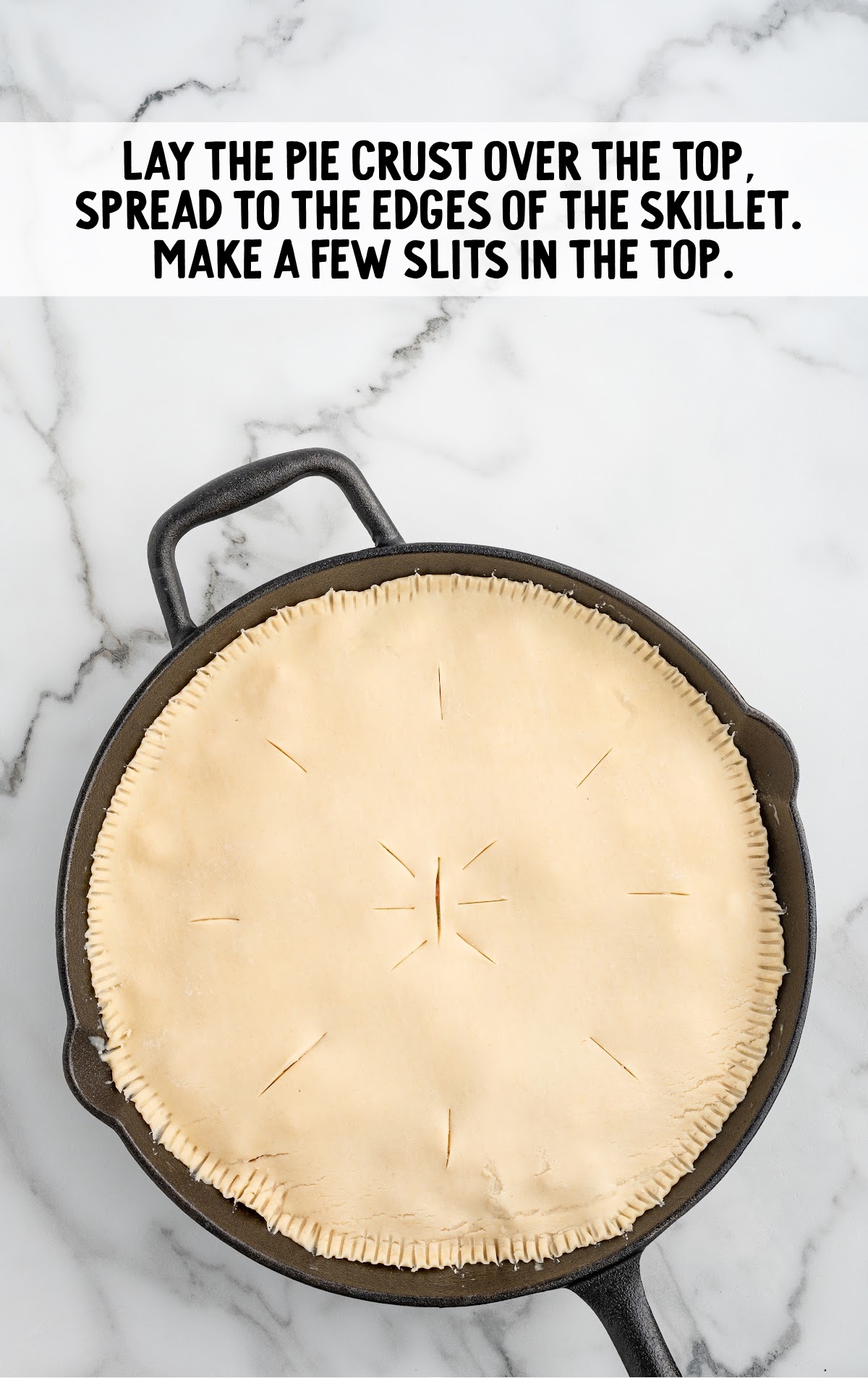 A pie crust is laid over the skillet pot pie filling.