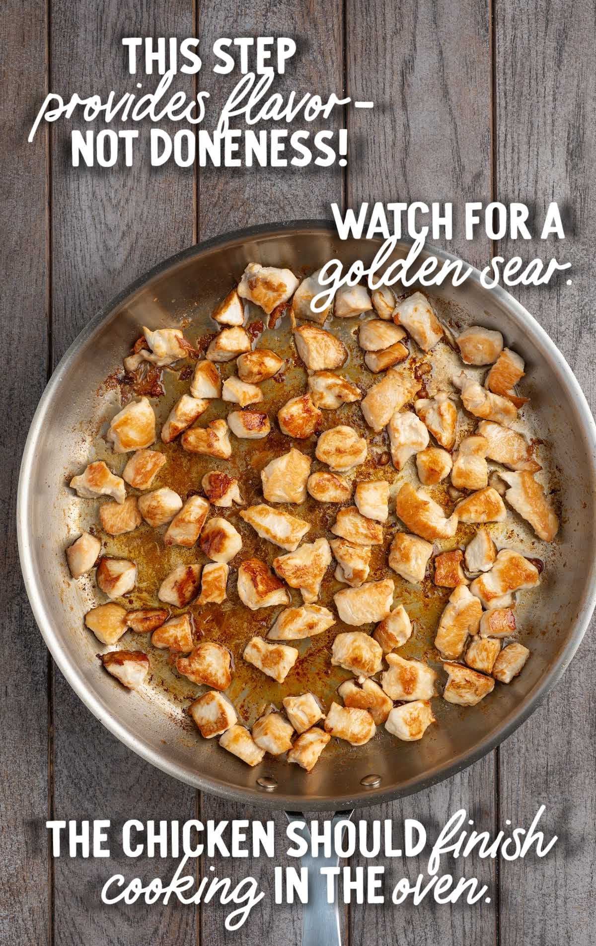 Diced chicken breast searing in a skillet with golden brown edges for spinach and artichoke chicken casserole.