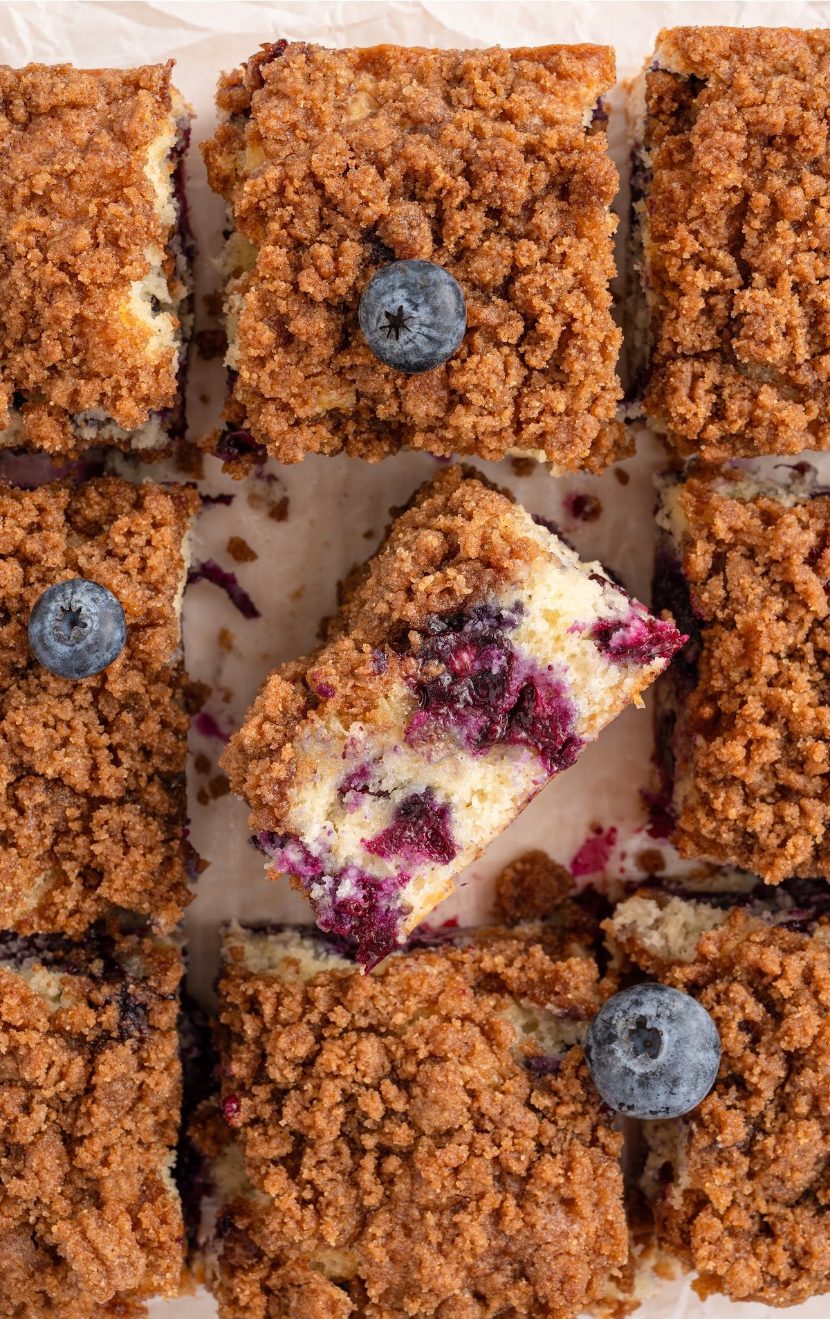 Overhead view of slces of Blueberry Coffee Cake. One is flipped on its side to show the moist blueberries.