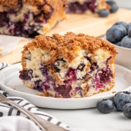 A piece of Blueberry Coffee Cake on a white dessert plate.