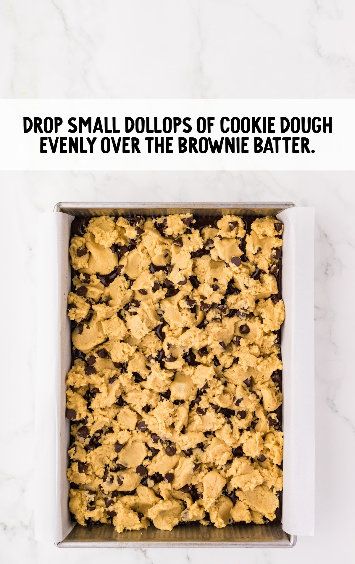 The cookie dough is broken into chunks and set over the brownies.