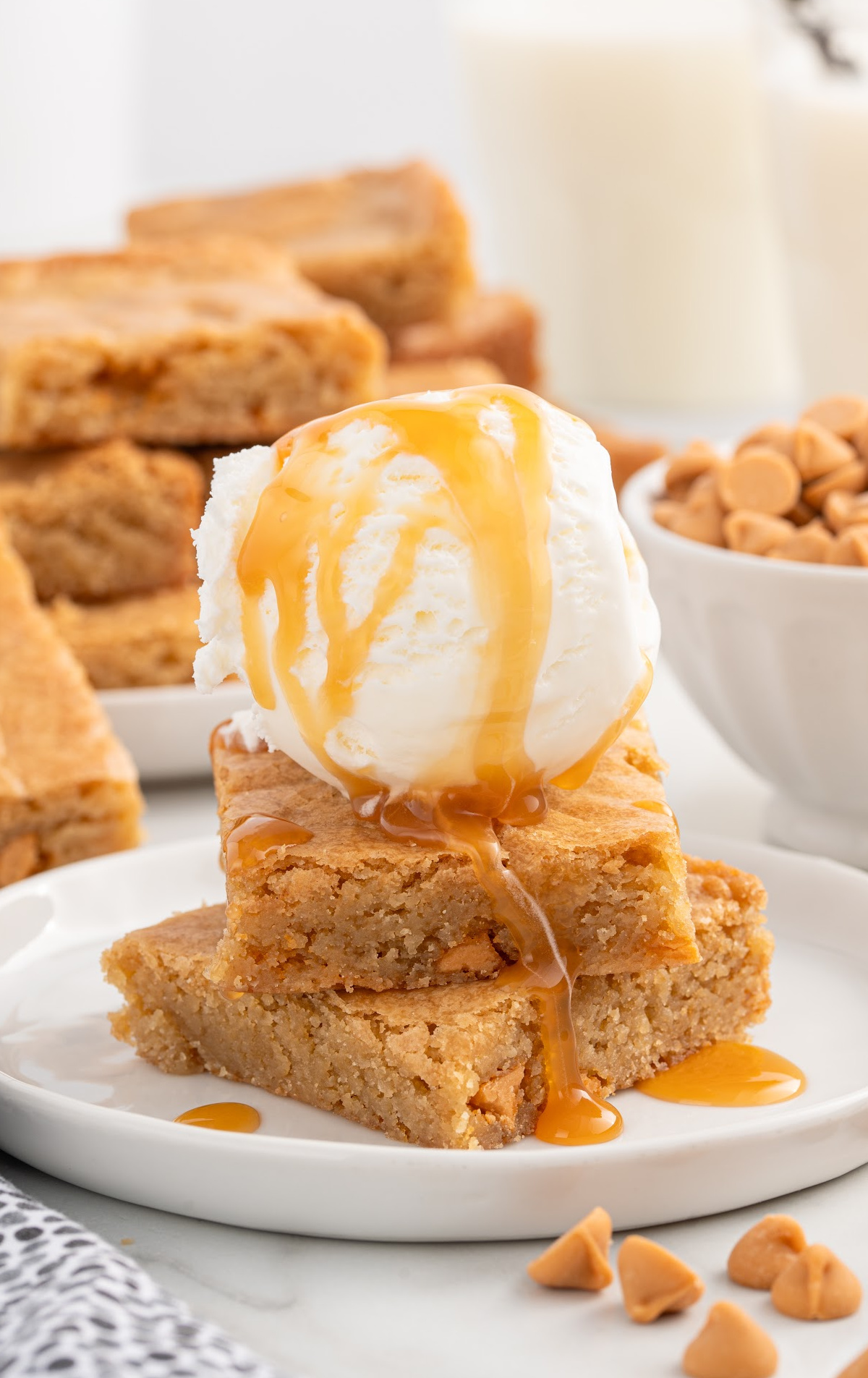 a close up shot Butterscotch Brownies stacked on top of each other and topped with vanilla ice cream on a plate