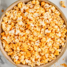 An overhead view of a bowl of cheese popcorn.