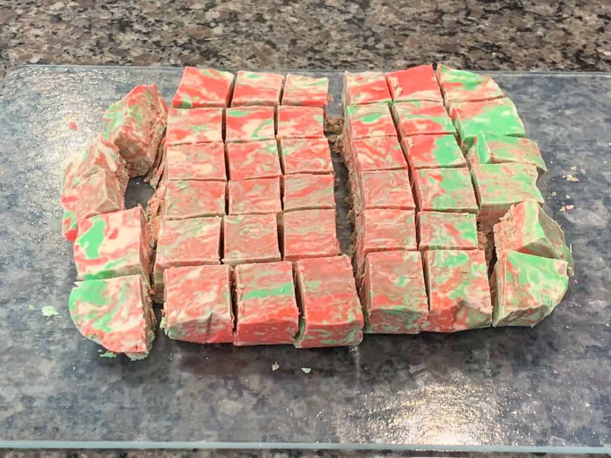 Squares of red, green and white fudge made with frosting on a clear tray, with the colors muddled together instead of swirled.