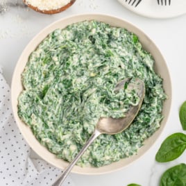 a bowl of creamed spinach with a spoon