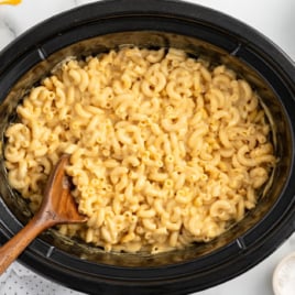 a crockpot of velveeta mac and cheese with a large wooden spoon