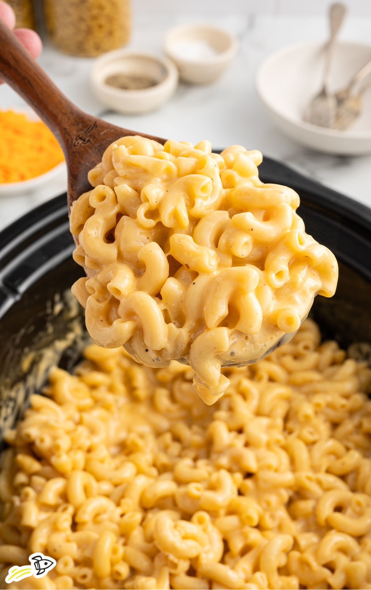 a crockpot of velveeta mac and cheese with a large wooden spoon