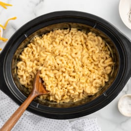 a crockpot of velveeta mac and cheese with a large wooden spoon