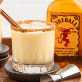 2 glasses of fireball eggnog beside a bottle of fireball whiskey.