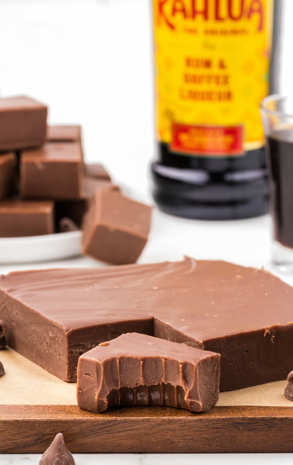 A slab of Kahlua Fudge on a cutting board. One piece is sliced out of it, and it has a bite out of it.