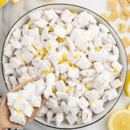 A large white bowl of Lemon Puppy Chow with a scoop coming out of it.