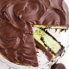 Mint chocolate cheesecake cut open with a slice laying on the serving tray.