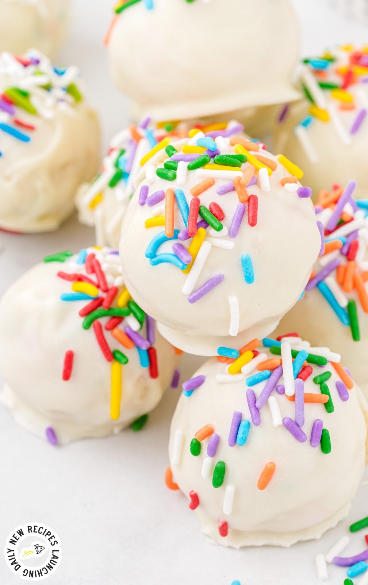 A plate of cheesecake truffles with rainbow sprinkles.