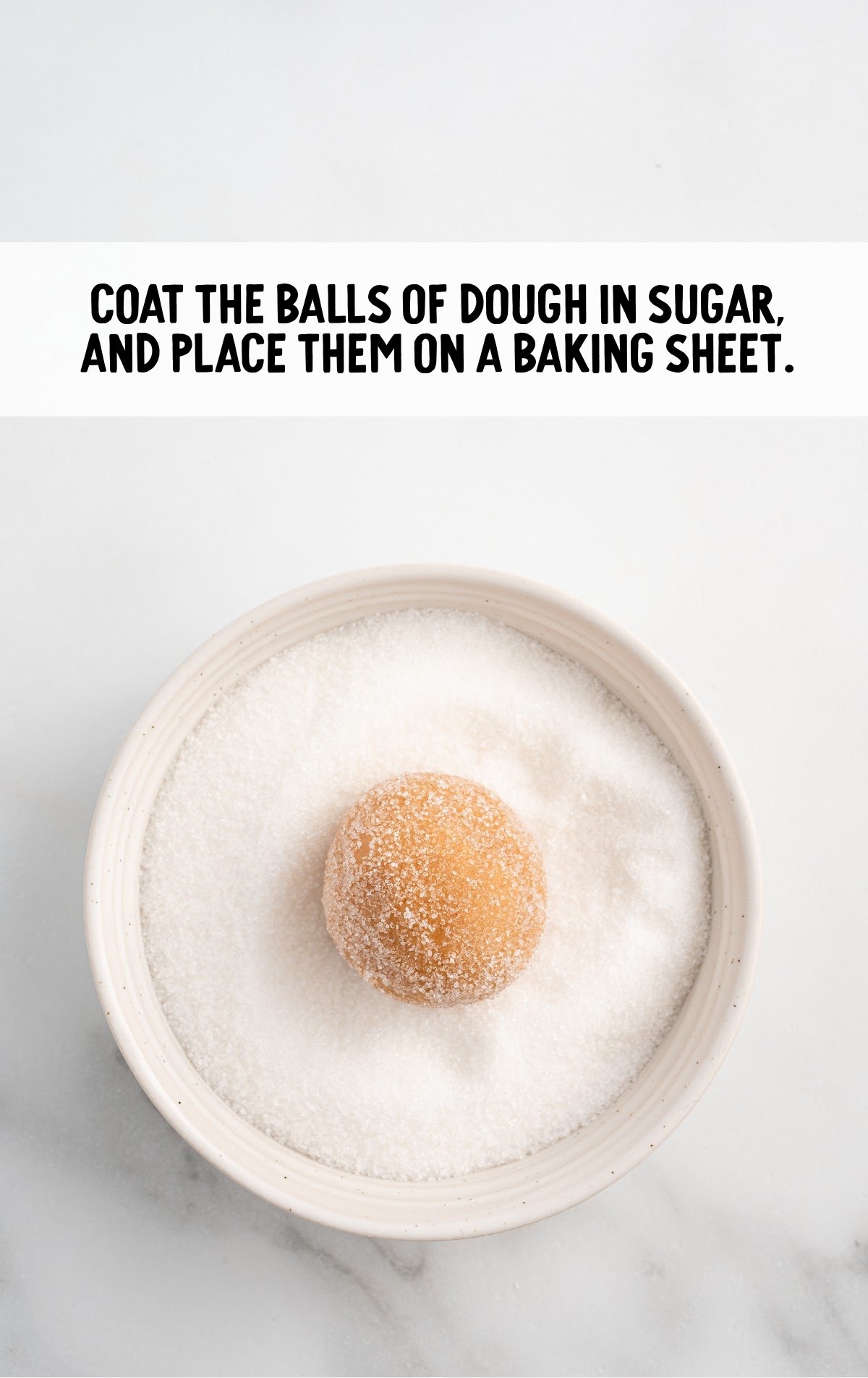 The cookie dough ball is rolled in sugar.