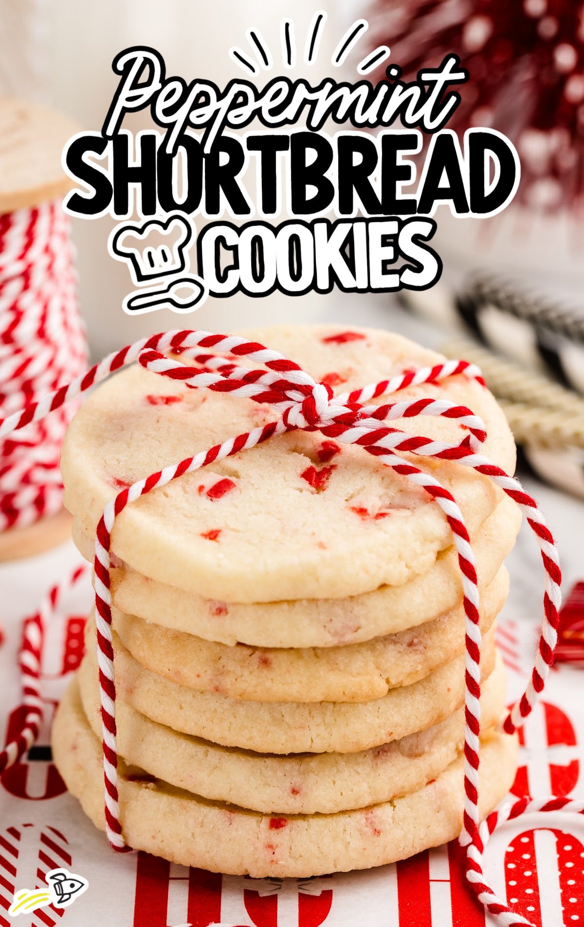 A stack of peppermint shortbread cookies are tied up with a red and white string like a present. 