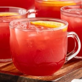 Christmas morning punch served in glass mugs with orange slices on a wooden tray