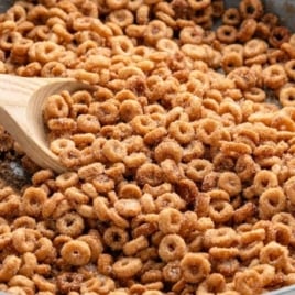 Skillet of hot buttered Cheerios being stirred with a wooden spoon