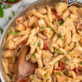 a skillet of chicken pasta garnished with basil