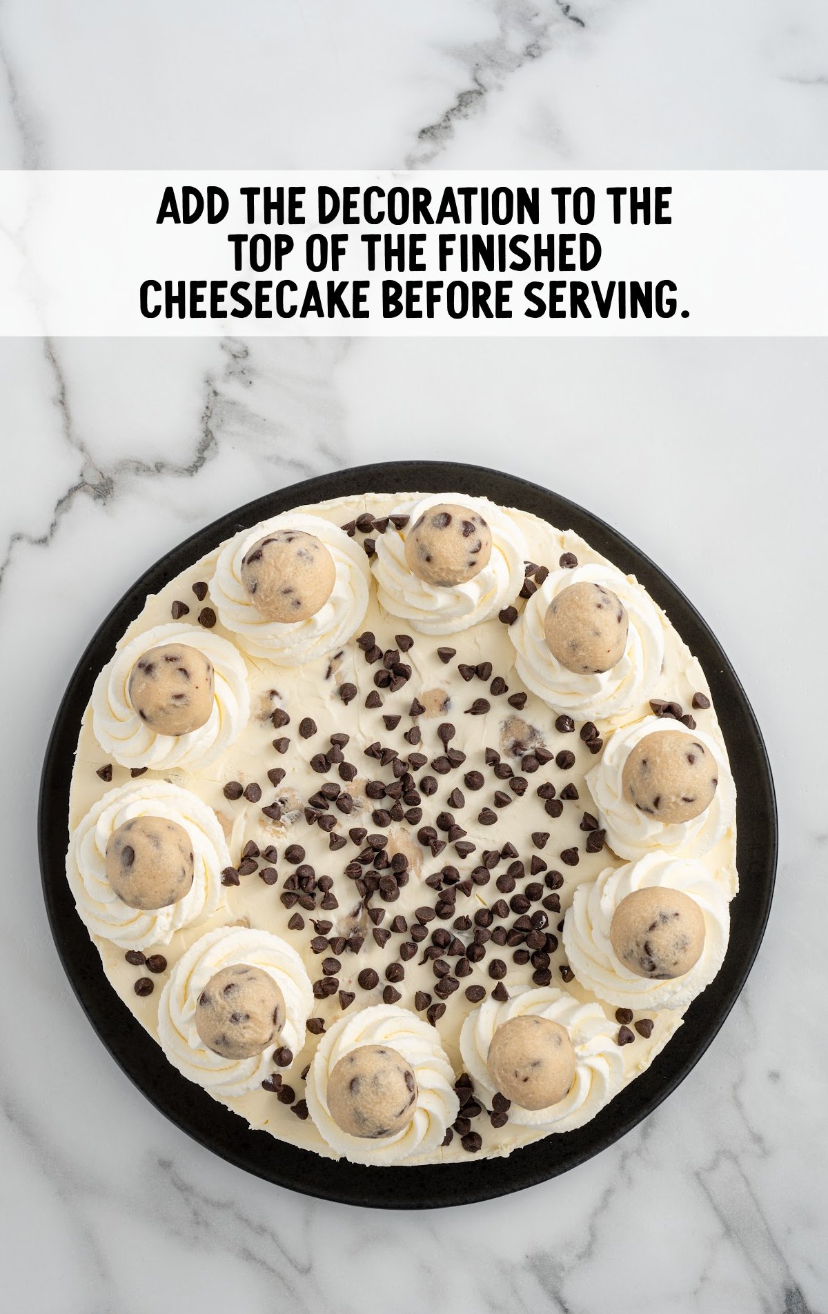 cookie dough cheesecake topped with frosting, chocolate chips, and cookie dough balls