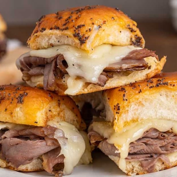 Stack of roast beef and provolone sliders on Hawaiian rolls served on plate