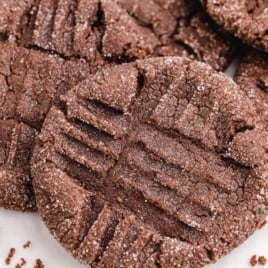 Close-up of chocolate crinkle cookies dusted with sugar, featuring a crisscross pattern pressed into their surface, reminiscent of a classic Chocolate Peanut Butter Cookies Recipe.