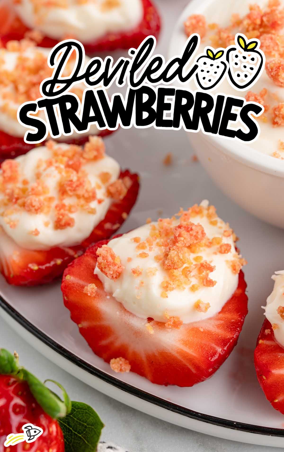 Cheesecake deviled strawberries arranged on a platter with a bowl of filling in the center