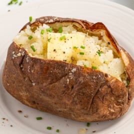 a baked potato topped with chives on a plate